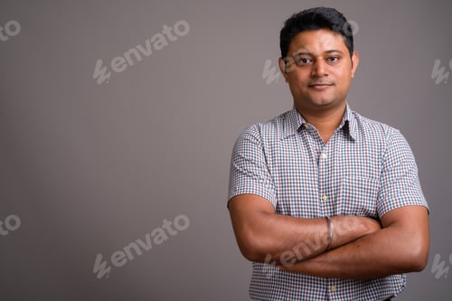 Preview: Portrait of young Indian businessman against gray background