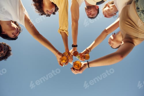 Preview: View from below of people that are cheering with beer bottles