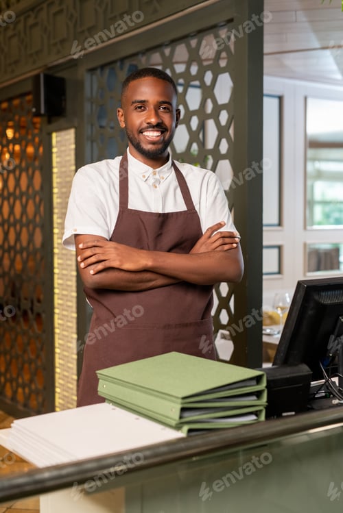 Preview: Young cheerful waiter of African ethnicity looking at you with toothy smile
