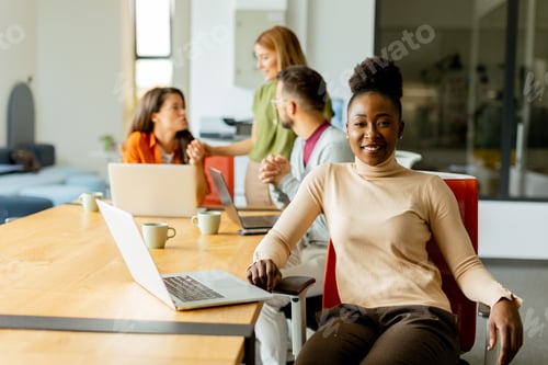 Preview: Cute Africam American woman with her young multiethnic startup team working in the modern office