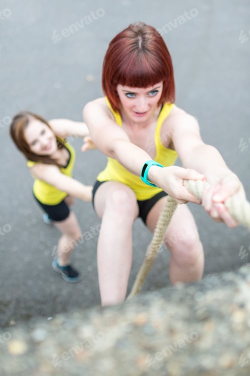 Preview: Young women climbing over wall with rope