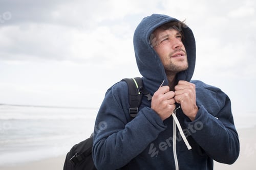 Preview: Man in a hoodie at the beach looking up