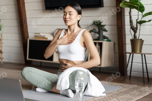 Preview: Meditation and online classes concept. Young woman training remote at home, sitting on rubber mat in