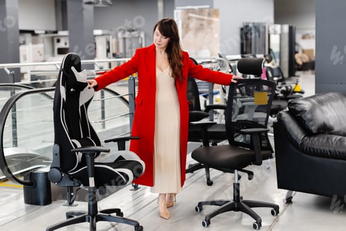 Preview: Elegant woman trying new office chairs in furniture store
