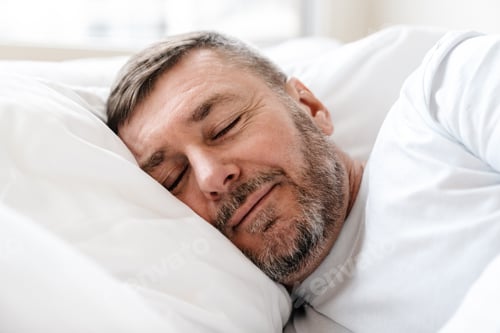 Preview: Peaceful adult unshaven man sleeping while lying in bed