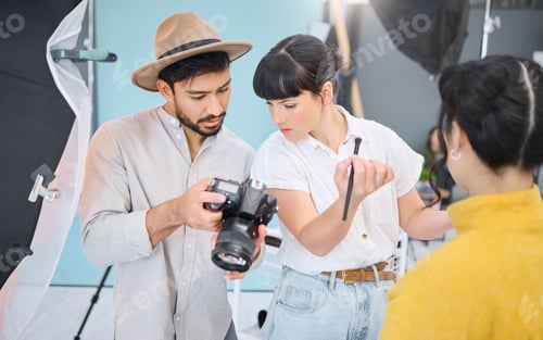 Preview: Makeup artist, photographer and model checking pictures during artistic, process and glamour shooti
