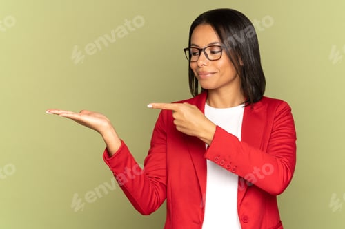 Preview: Confident mix race business woman in red jacket point finger to open palm demonstrate object product