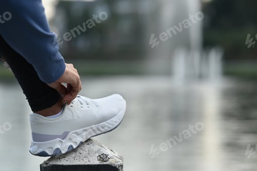 Preview: Athletic woman tying shoelaces and get ready for jogging and workout.