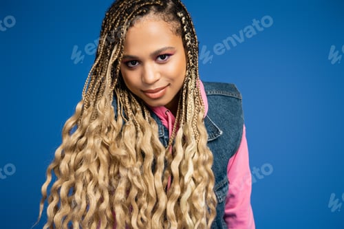 Preview: charming african american woman with dreadlocks and long hair looking at camera on blue background