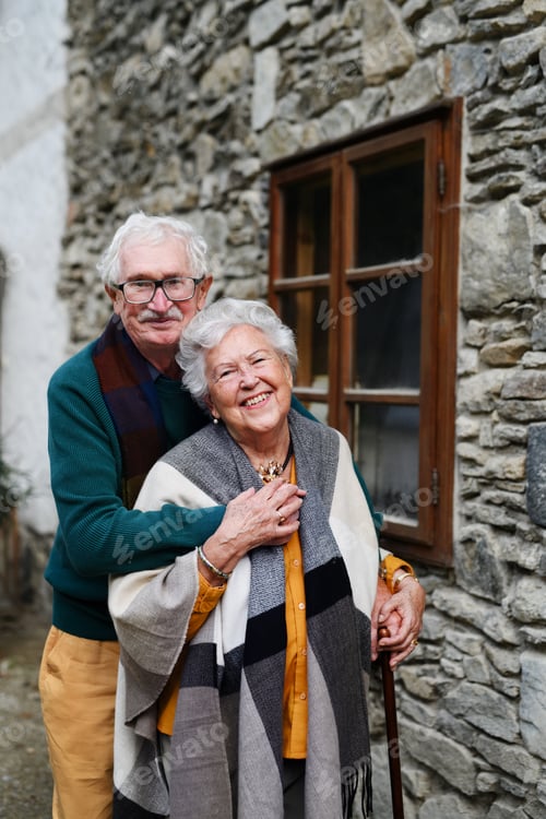 Preview: Happy senior couple posing near old countryside house.