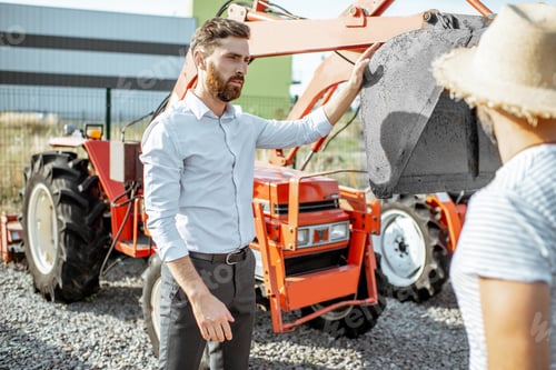 Preview: Agronomist with salesman near tractor at the agricultural shop