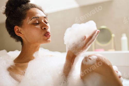 Preview: A happy woman bathing in a foamy spa tub, gesturing artfully with eyelashes
