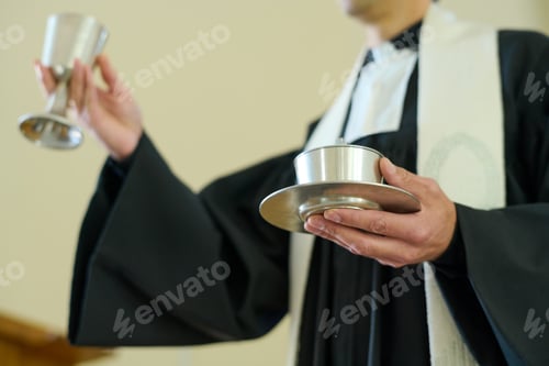 Preview: Catholic priest holding cups with wine and unleavened bread for oblation