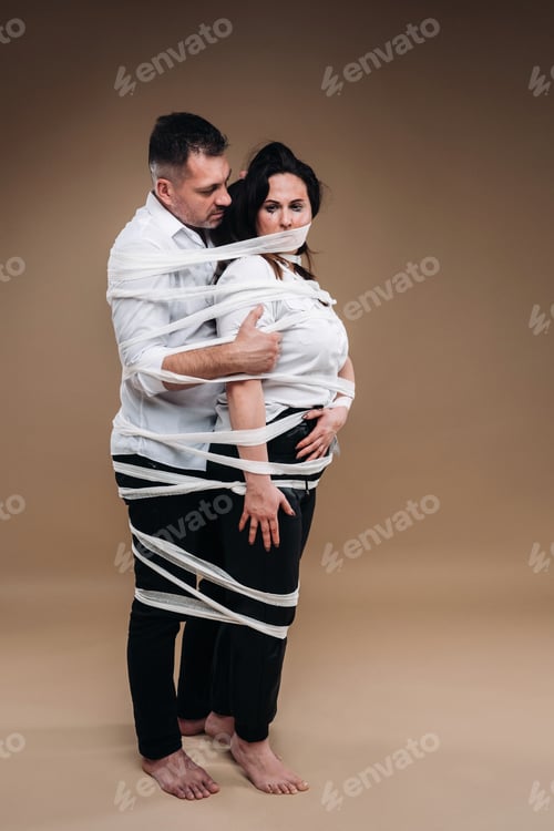 Preview: An aggressive man embraces a battered woman and is wrapped in bandages together. Domestic violence