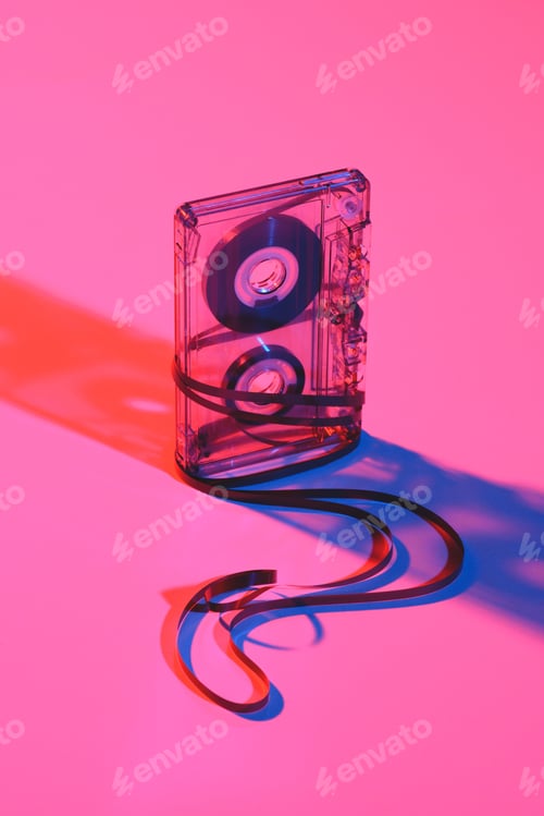 Preview: close up view of retro audio cassette and tape on pink backdrop