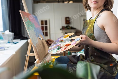 Preview: Close-up view of young inspired girl painting in light studio