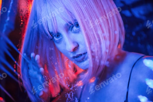 Preview: Posing for camera. Stylish woman with white hair is behind wet transparent plastic sheet