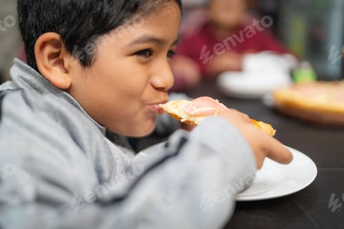 Visualização: Garoto latino comendo pizza em um pequeno restaurante com a família