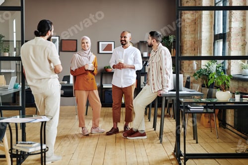 Preview: Group of happy young Muslim white collar workers having talk at coffee break