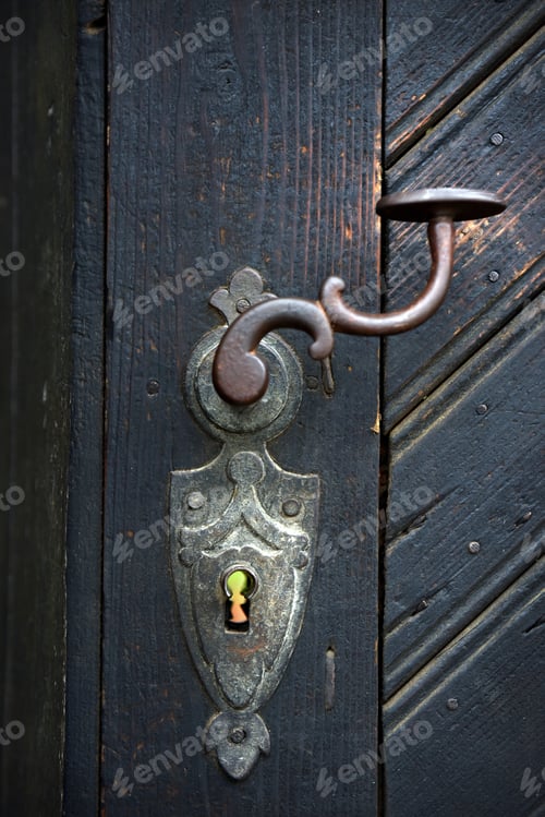 Preview: Ornamental vintage iron door handle on a wooden door