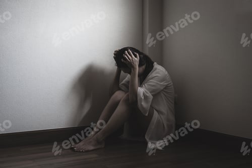 Preview: Depressed and stressed woman sitting on the floor alone head in hands in the dark room