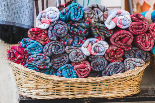 Preview: Rolls of multicolor towels in a wicker basket on a shop window