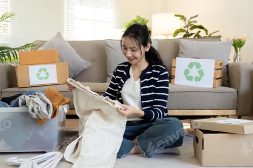 Preview: Woman pack box with used clothes for reuse. Reusing, recycling material and reducing waste in