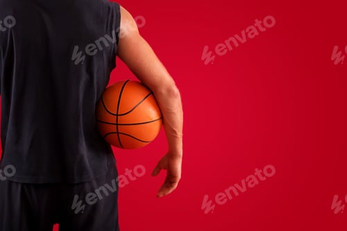 Preview: Closeup of millennial basketball player holding ball over red studio background, space for text