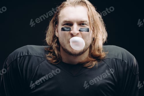 Preview: Determined American football player posing with painted face and chewing gum