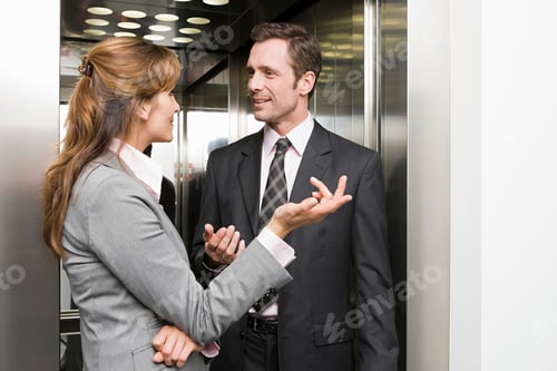Preview: Two professionals engaged in a conversation inside an elevator.