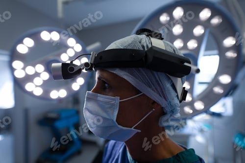 Preview: Female surgeon standing in operation theater and wearing an operation mask and a head lamp