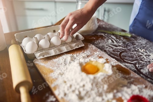 Preview: Attentive baker picking an egg to add to the dough mix