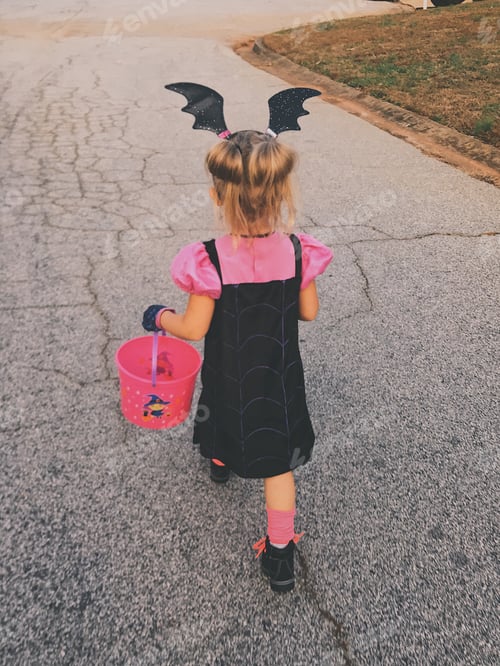 Preview: A little girl walks down the street on Halloween wearing her Halloween costume carrying her candy.