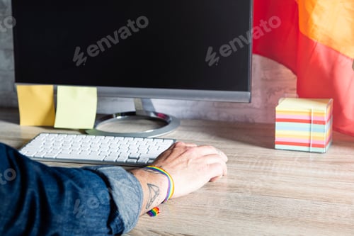 Preview: LGBTQIA culture. Man working in office with LGBT accessories.