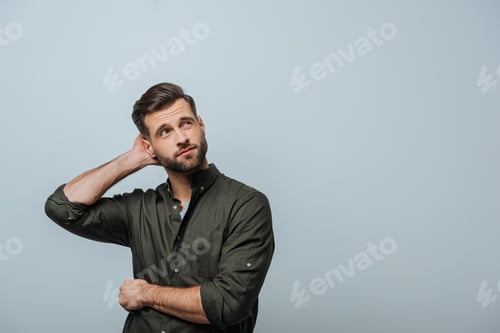Preview: Pensive man with hand near head looking up isolated on grey