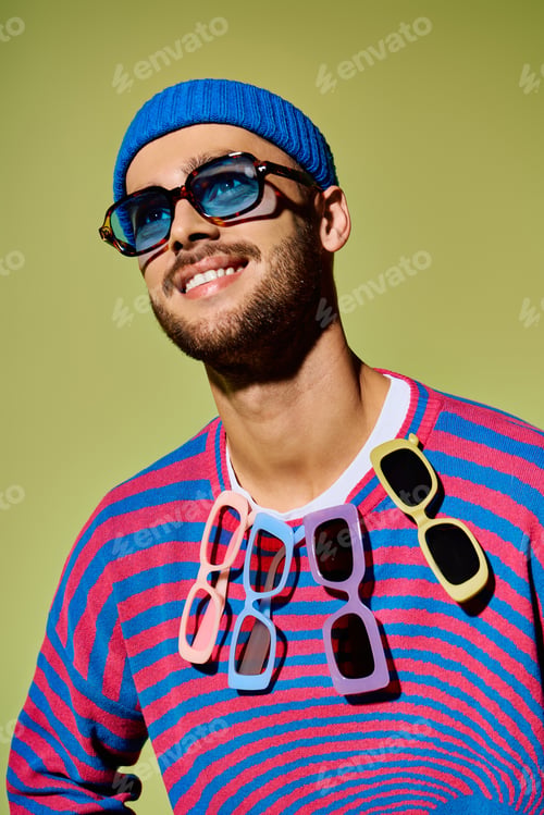 Preview: Young man showcases vibrant fashion sense with stylish sunglasses in studio setting