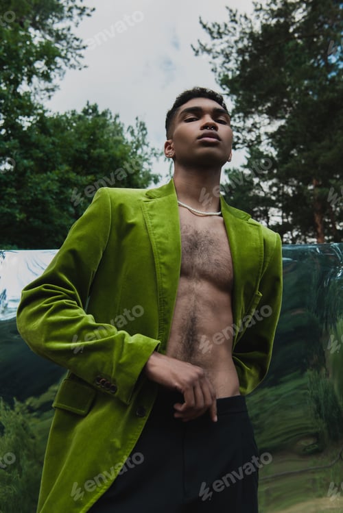 Preview: low angle view of african american man in green velvet blazer near flexible mirror in park