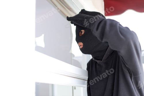 Preview: Robber in Balaclava Cautiously Peeking Through Residential Window to Spy on The Inside.