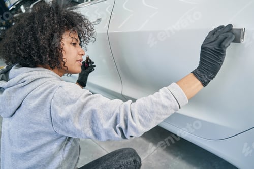 Preview: Focused experienced young female detailer polishing client vehicle