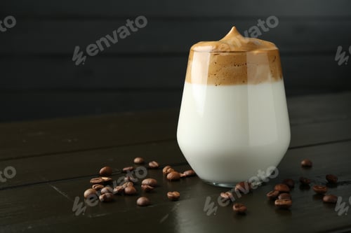 Preview: Delicious dalgona coffee in glass and beans on wooden table, closeup. Space for text