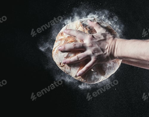 Preview: Closeup of male hands put fresh bread on black background with copy space for your text