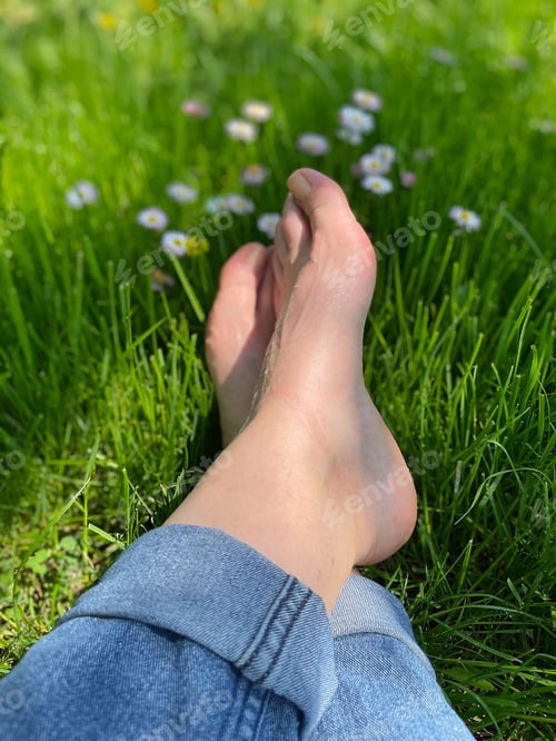Preview: A woman with bare feet is resting on the grass