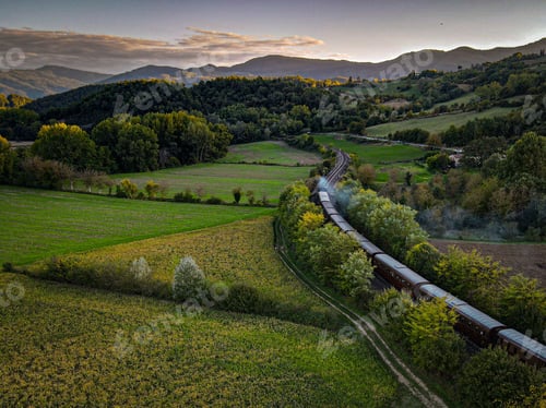 Preview: Aerial view of vintage train in lush countryside at sunset.