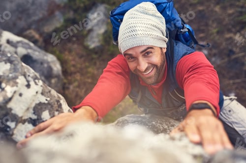 Preview: The view will be worth the effort. Shot of a happy hiker climbing over rocks on a mountain trail.