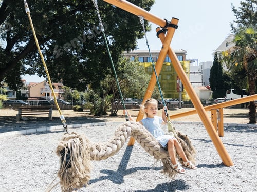 Preview: Little girl swings on a swing in the form of a braid on the playground
