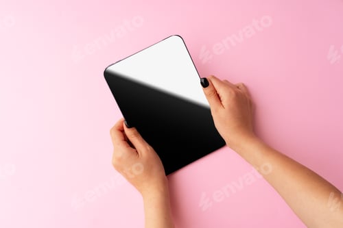 Preview: Woman hands holding digital tablet above pink background