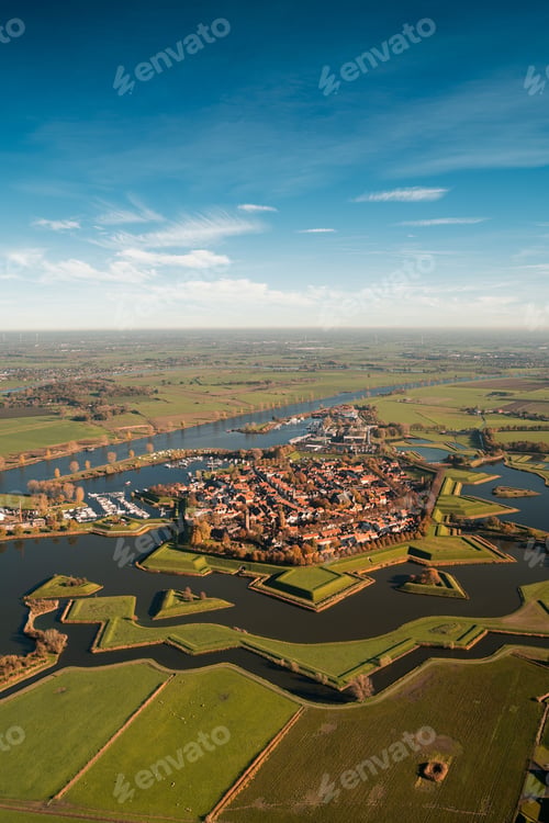Preview: Vertical aerial shot of a river surrounded by plowed fields separated by patterned lines
