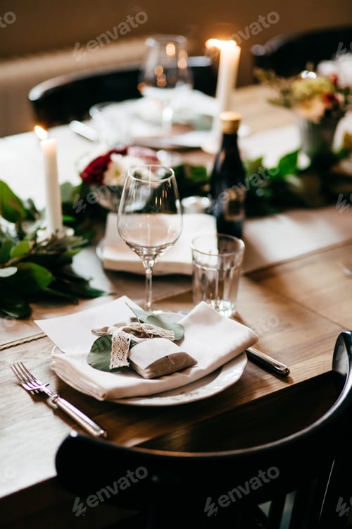Preview: Table served with glasses, plate, drinks, forks and knives, burning candles