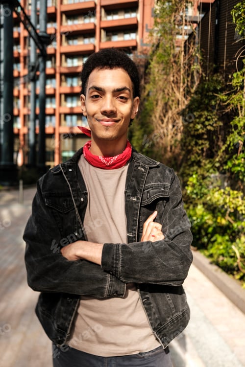 Preview: Young man smiling with folded arms in urban setting