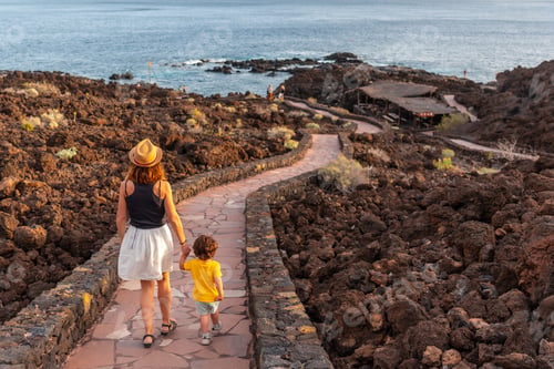 Preview: Mother and son walking on a path towards the beach at sunset on the beach of Tacoron on El Hierro